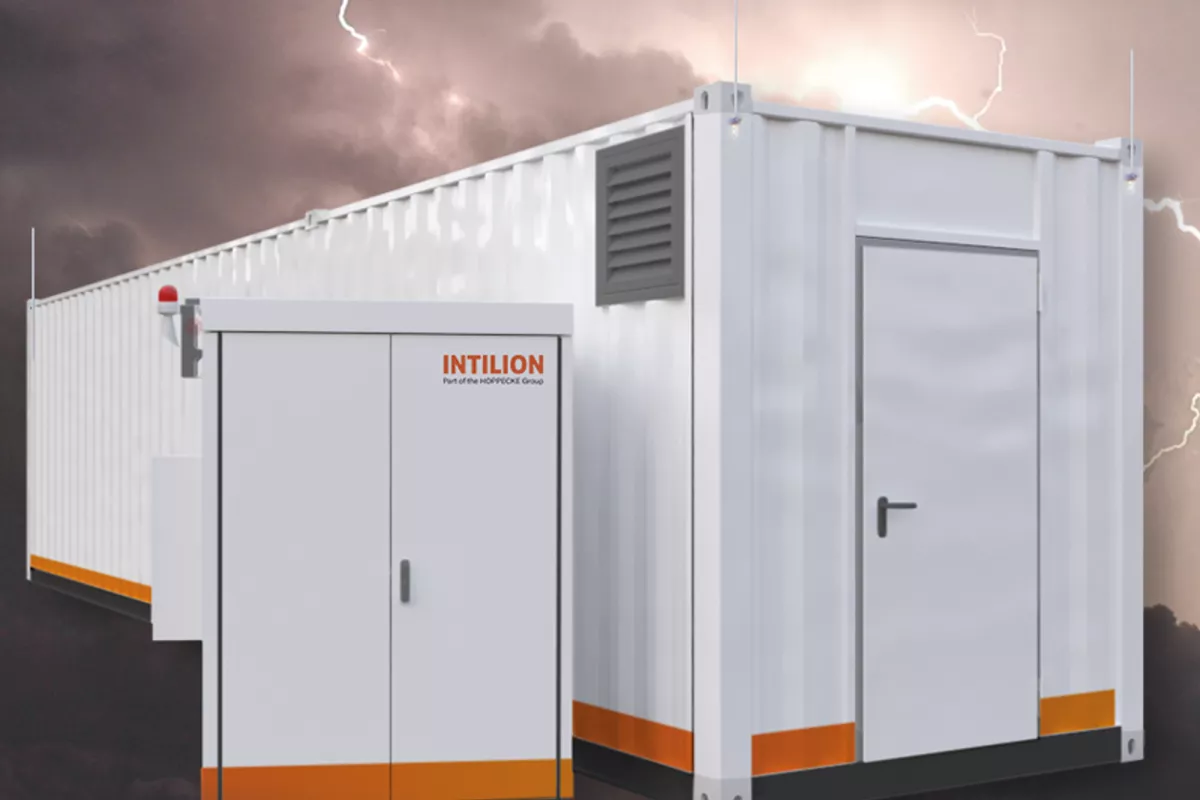 Modulares, weißes Containerstromaggregat mit orangefarbenen Akzenten, daneben ein kleineres Bedienfeld, vor dem Hintergrund eines Gewitters mit Blitzen.