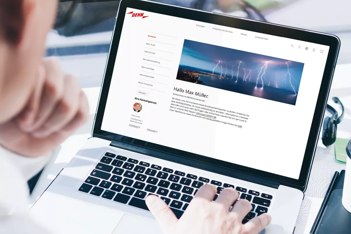 A person using a laptop, viewing a webpage featuring a profile and a header image of wind turbines against a cloudy sky.
